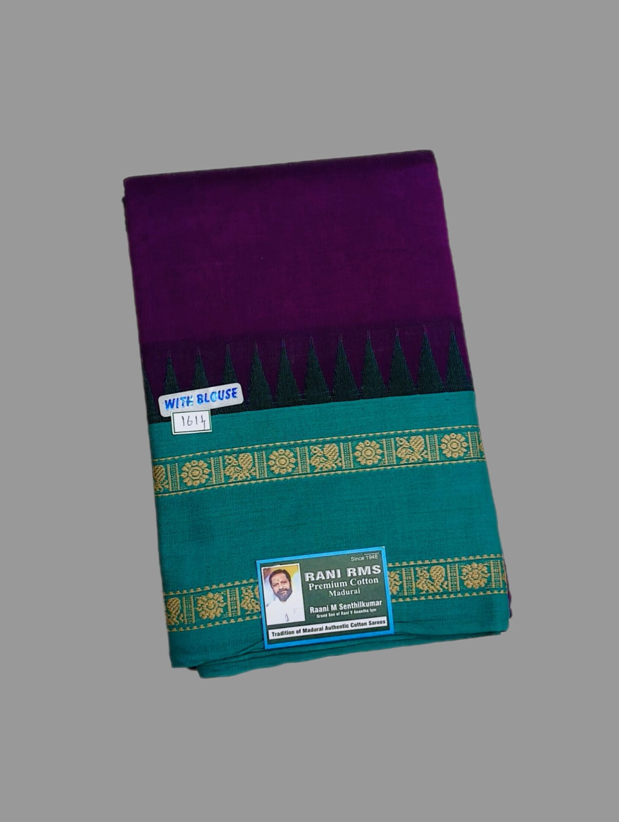 A folded purple and teal saree with gold zari border detailing, featuring a white size label and a brand tag by Rani Rams on a solid gray background.