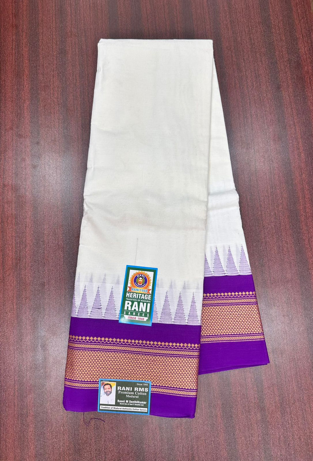 White saree with purple border on a wooden surface