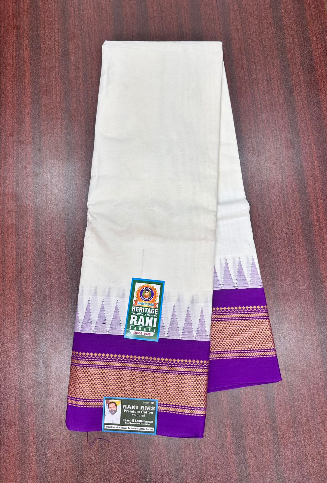 White saree with purple border on a wooden surface